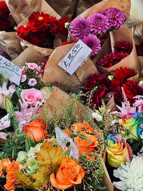 A vibrant assortment of fresh flower bouquets displayed together, featuring a variety of flower types, including bright red dahlias, purple chrysanthemums, soft pink roses, orange roses, and multicolo